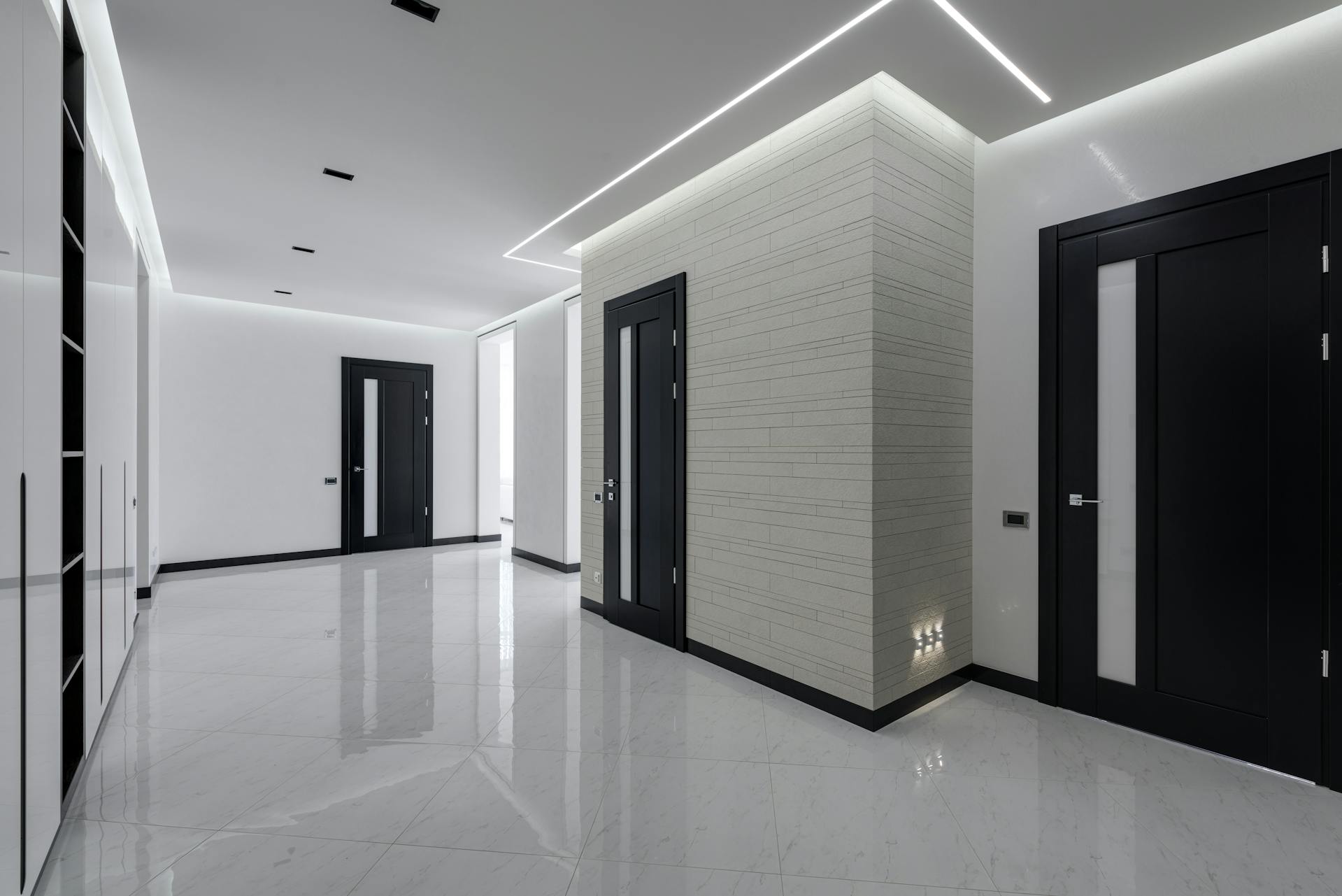 Interior design of luxury house having black doors with white paint on walls and white marble reigns on floor.